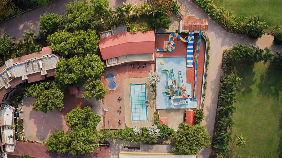 Waterpark at DGV Resort by Treat, Silvassa featuring colourful slides, swimming pools, surrounding trees, and adjacent open lawns and buildings.