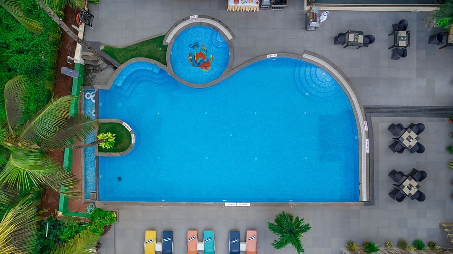 Aerial view of the main pool area with lounge chairs and surrounding greenery - Golden Tulip, Candolim, Goa