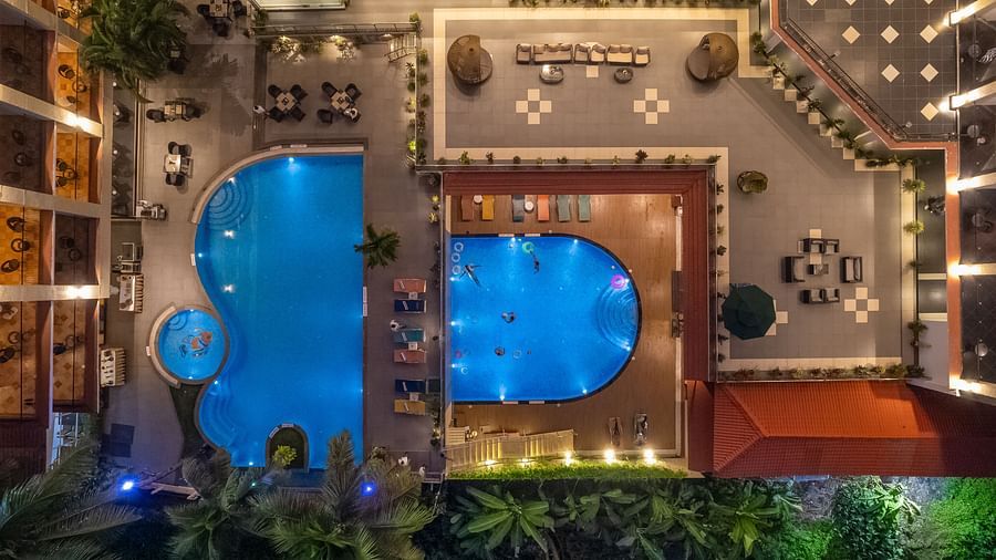 Aerial night view of our hotel near candolim beach, featuring illuminated swimming pool, surrounded by lush greenery and decorative lighting - Golden Tulip, Candolim, Goa