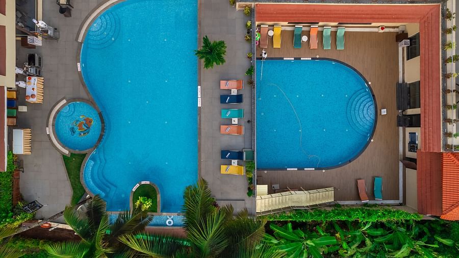 an Aerial view of the w-shapped swimming pool, with sun loungers neatly arranged around it - Golden Tulip, Candolim, Goa