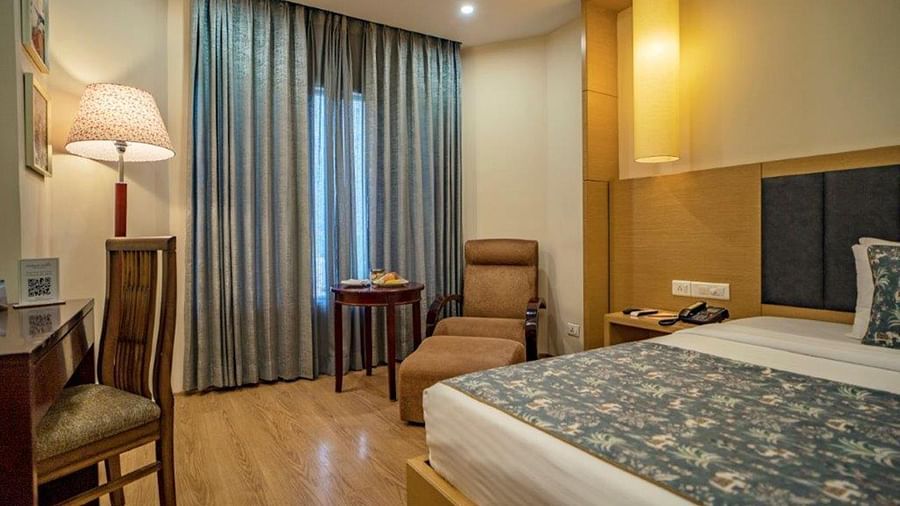 Standard bedroom with two chairs, lamps, and cosy atmosphere at Golden Tulip, Udaipur.