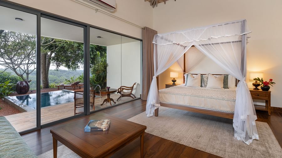 A luxurious bedroom with a canopy bed, warm lighting, and glass doors leading to a private pool and garden - Suite with Private Pool at Heavensa Villas and Suites by the Clarks, Galle