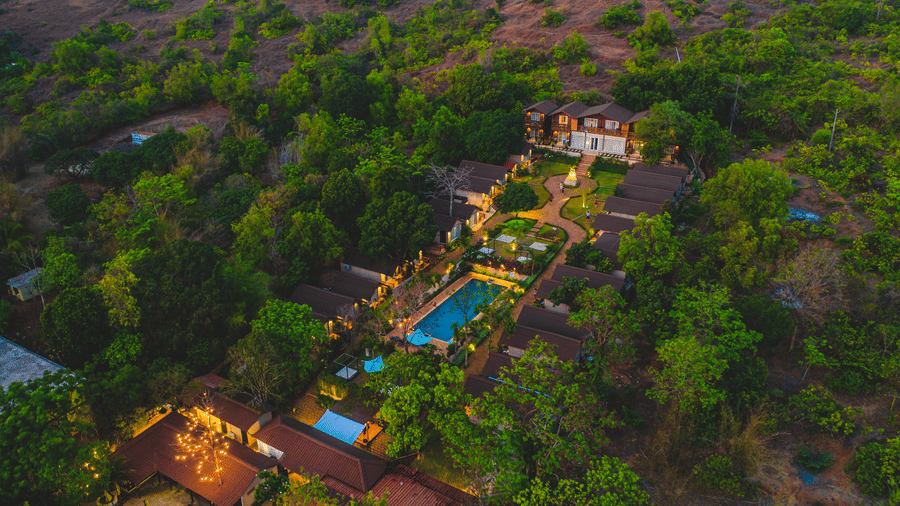 Aerial view of our resort in Mandrem featuring a night panorama with the swimming pool, the surroundings and the cottages 64