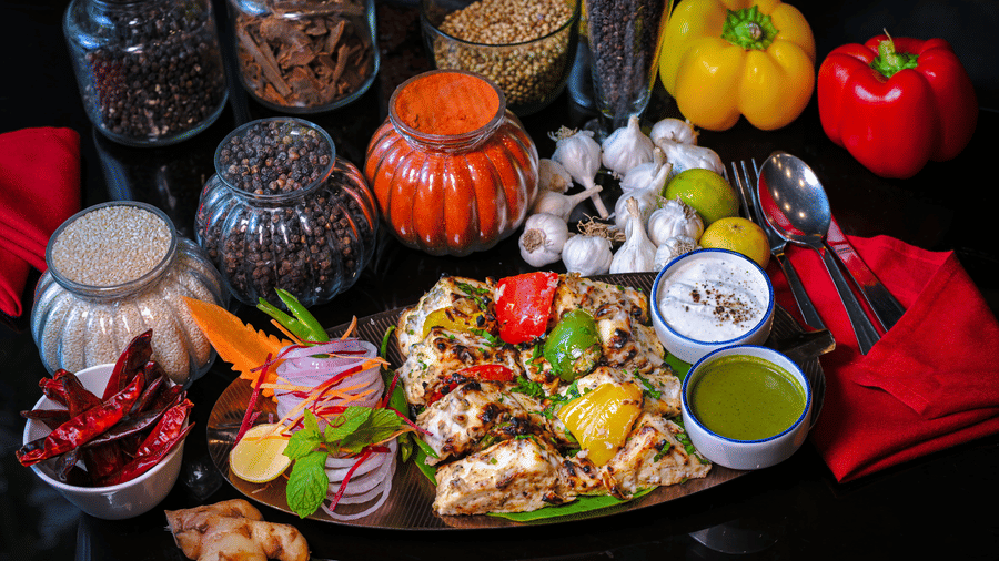 A special dish served on a plate with capsicums and spice bottles placed in the backdrop for decoration at Clarks Hotels.