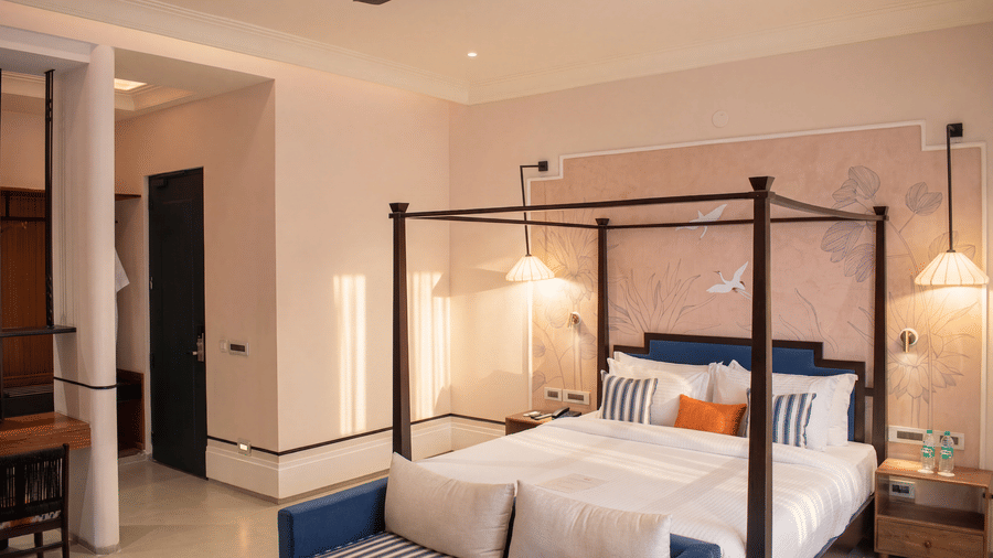 An elegant bedroom featuring a four poster king size bed, attached sofa, bedside lamps, and side desk at The Sierra - By The Lake.