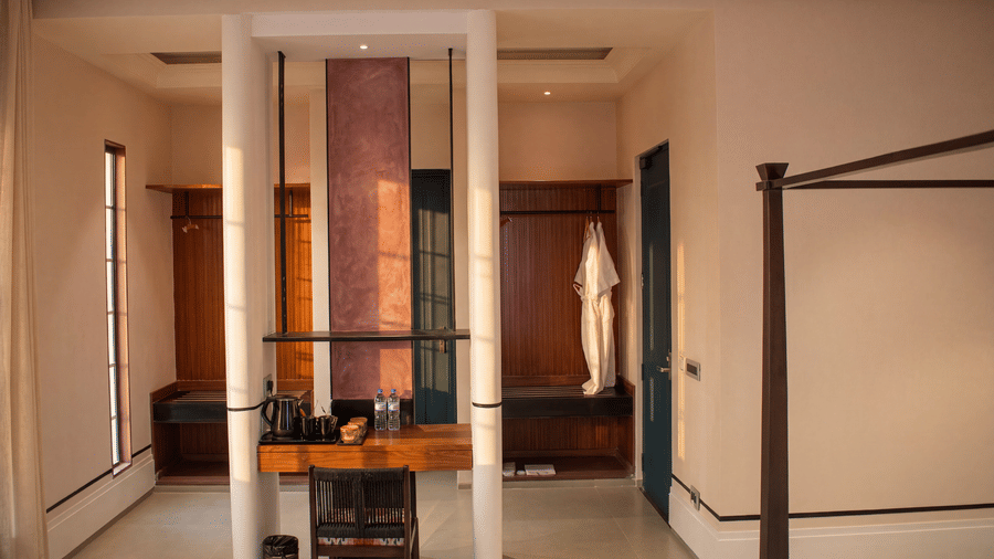 A dressing alcove with a wooden vanity desk, chair, support pillars, and hanging bathrobes at The Sierra - By The Lake.
