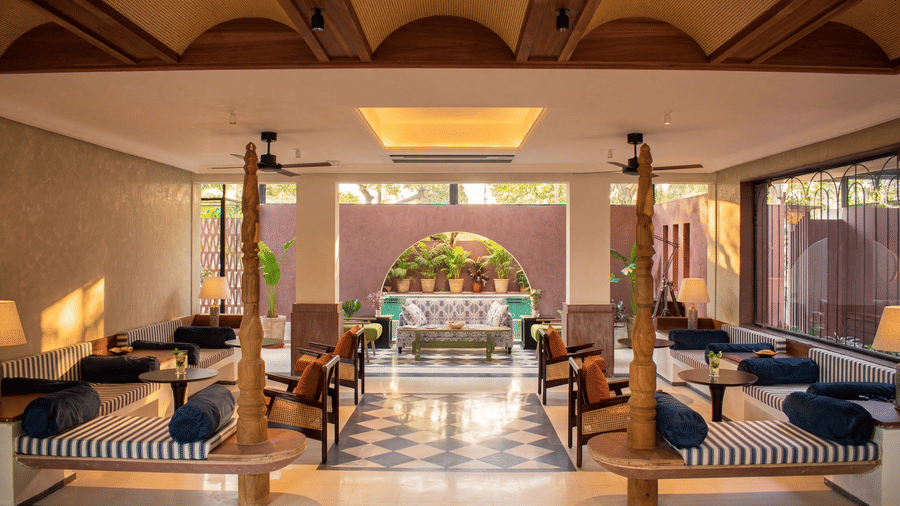 The indoor lounge seating area at The Sierra - By The Lake features wooden pillars, cushioned benches, low tables, and large windows overlooking the grounds.