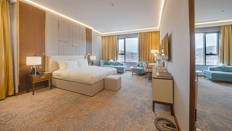 Drawn curtains offering views of the hills beyond the glass windows in the Deluxe King Room at Grand Iva Hotel, Abha.