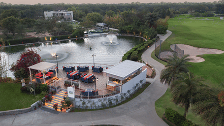 aerial view of a building next to a waterbody with fountains - Karma Lakelands.