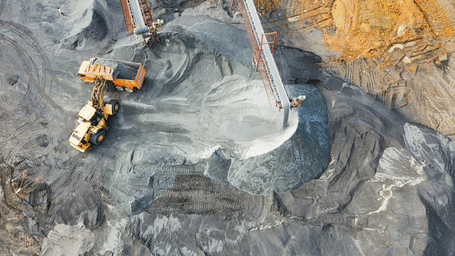 Aerial view of an industrial quarry with conveyor belts and heavy machinery moving gravel and stone.