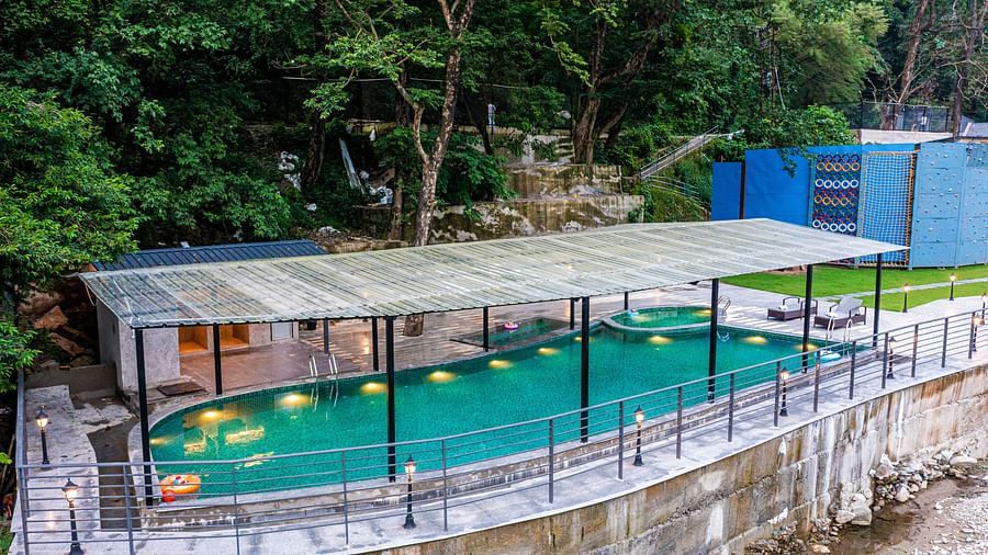 Aeriat view of swimming pool at DLS Divine Resort and Spa with serene views and lounge chairs.