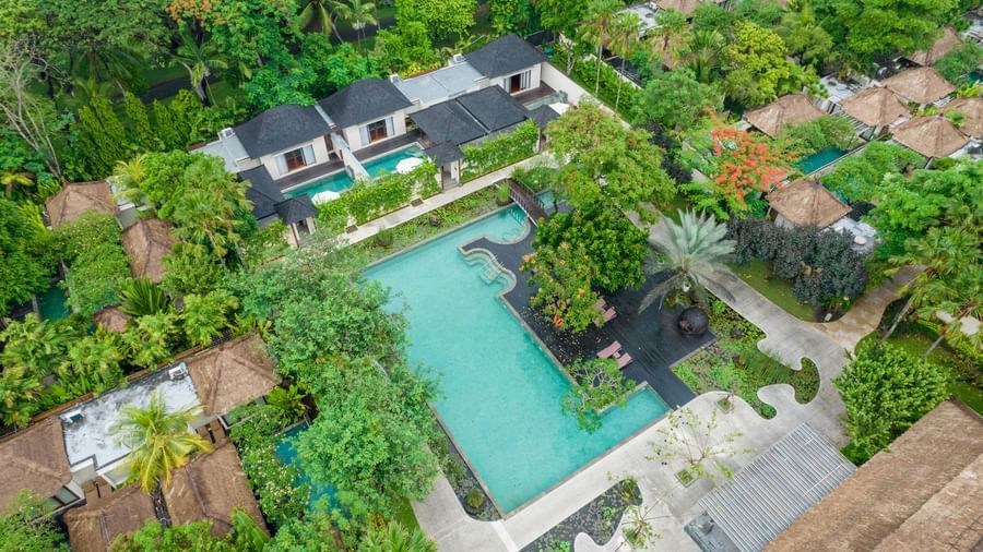 Overhead view of a hotel with a large, tree-lined pool area.
