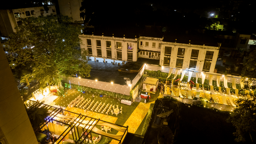 Aerial night view of the Gemini Continental lawn, showcasing a sprawling event space with tiered seating, festive string lights, and elegant canopy draping.