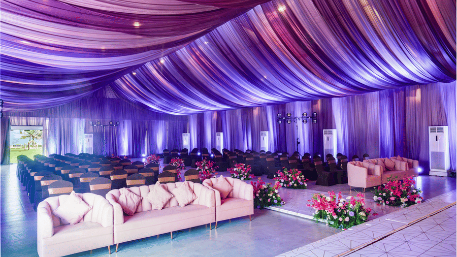 An indoor hall featuring purple draped ceiling, sofa seating rows, and floral aisle decor - Grande Bay Resort & Spa, Mamallapuram