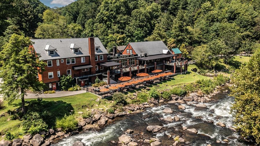 a beautiful facade image of our resort taken on a bright morning featuring a river stream flowing right in front of it - Historic Tapoco Lodge
