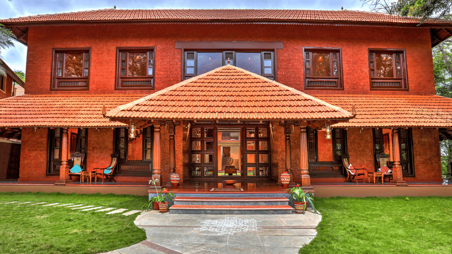 Facade view of the Malnad Palace at Hoysala Village Resort, Hassan with a stone pathway leading to it.