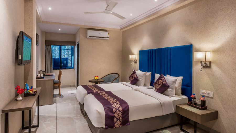 Lords Eco Inn Executive bedroom with a large bed, a headboard, a ceiling fan, and simple wooden furniture.