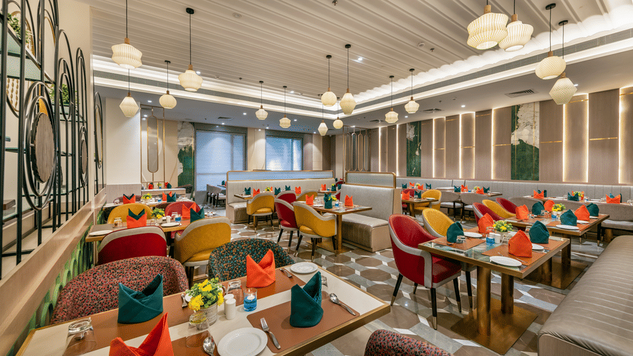 Restaurant buffet counter and dining area with colorful table settings at Lords Inn Somnath, offering a warm and inviting atmosphere.