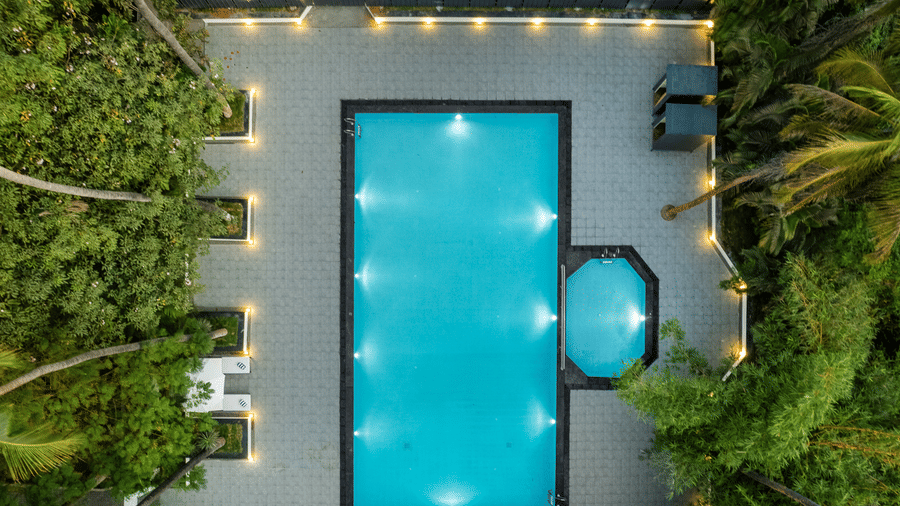 Aerial view of a swimming pool surrounded by greenery at Mango Hill Resort, Coimbatore