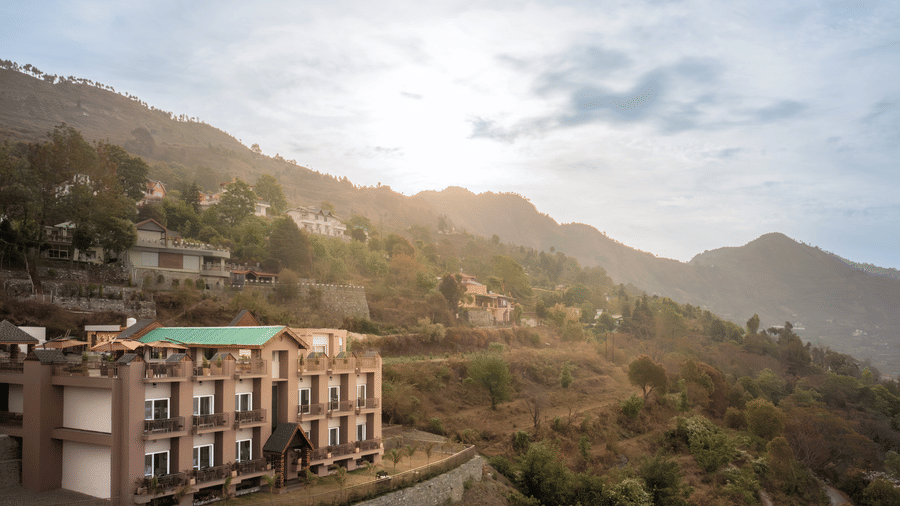 facade of the Leisure hotel surrounded by greenery with hills on the background during day v