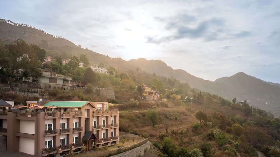 facade of the Leisure hotel surrounded by greenery with hills on the background during day v