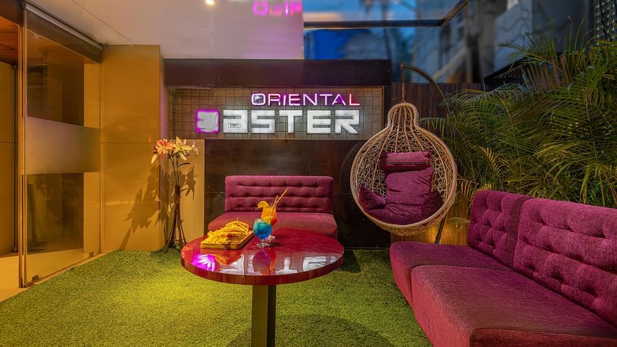 View of the lobby area at Oriental Aster, Mumbai, featuring cushioned sofas arranged around a table and a signboard displaying 'Oriental Aster'.