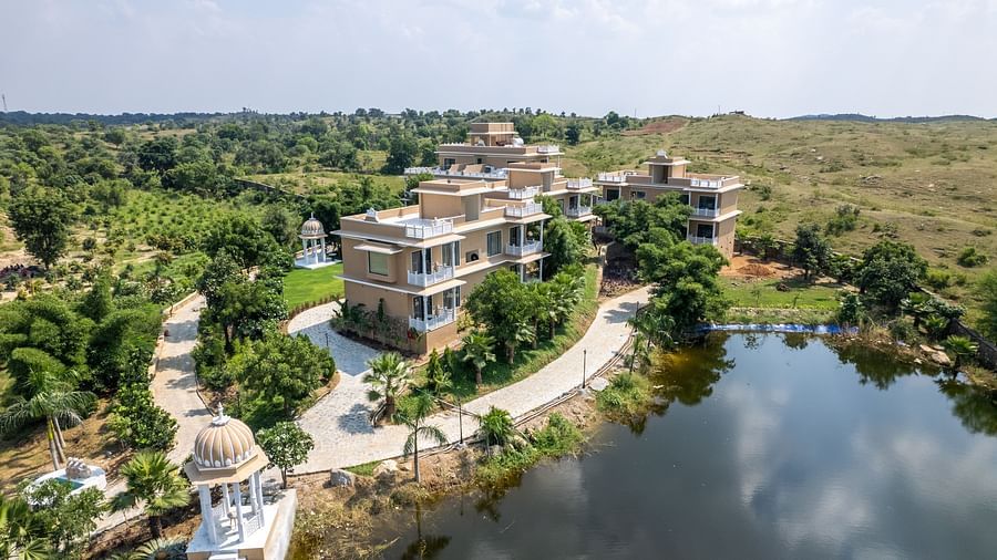 Buildings nestled along a picturesque winding pathway near the water - Rajbagh Wellness, Udaipur