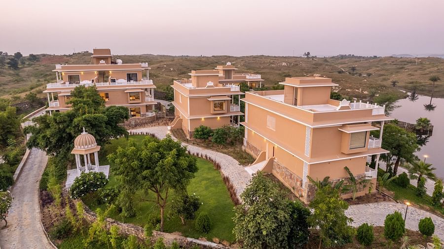 An aerial image of buildings at our wellness retreat in Udaipur with a water body near the buildings - Rajbagh Wellness, Udaipur