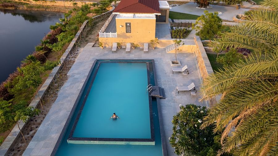 An aerial shot of a woman performing an asan in a swimming pool at our tranquil wellness centre - Rajbagh Wellness, Udaipur