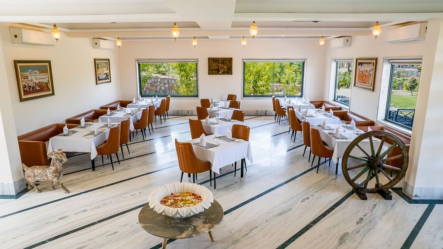 An image of a dining area with neatly arranged tables and chairs - Rajbagh Wellness, Udaipur