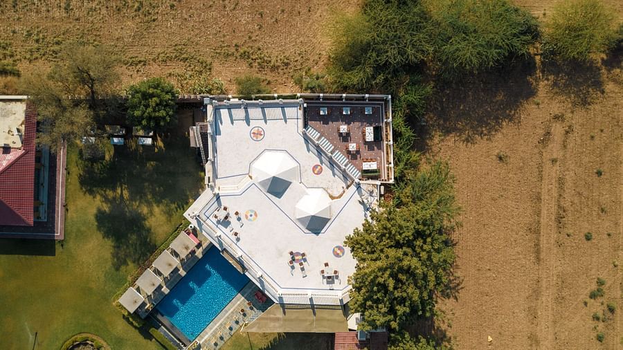Aerial view of a dining area with a swimming pool on the side at Surpura Bagh.