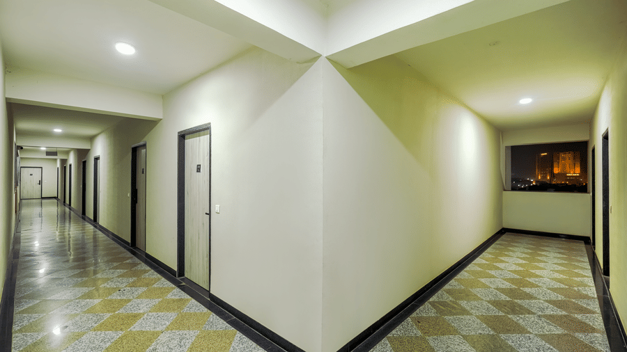 The corridor at Urban Suites by BluSalzz, Jaipur, featuring doors, a long hallway, and tiled floors.