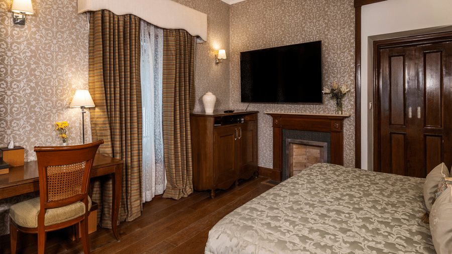 image of a king size bed with a work desk and a wall mounted TV at the Club Rooms at The Claridges Nabha Residence