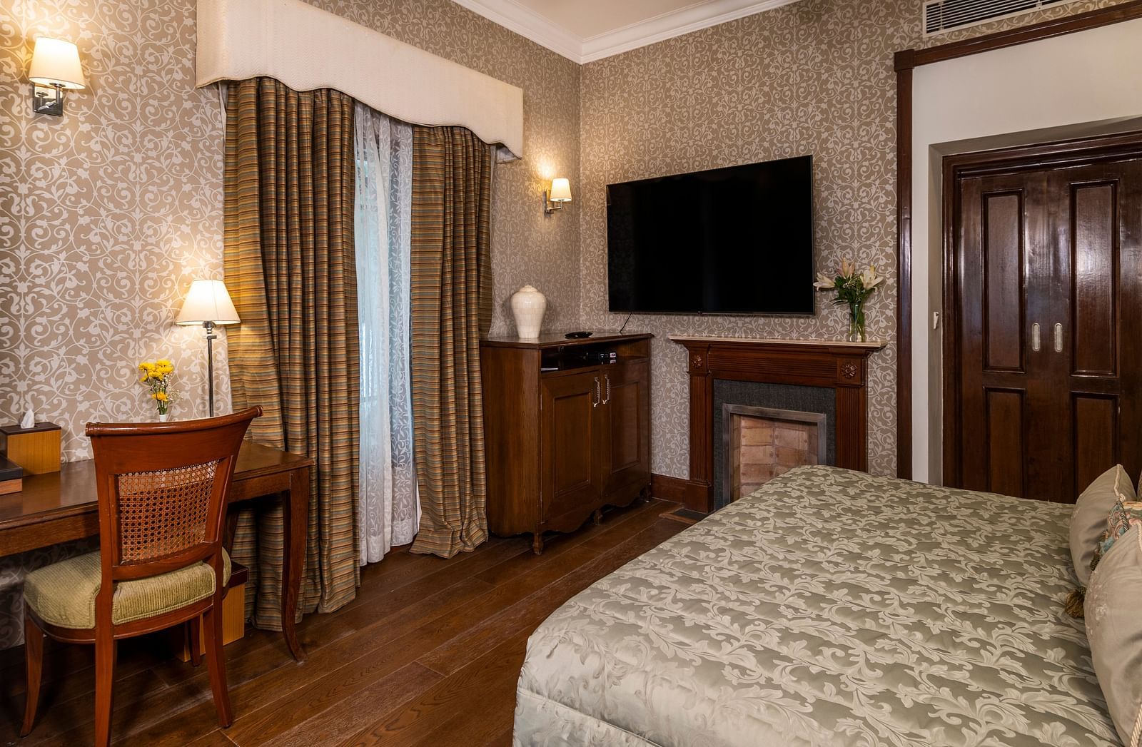 image of a king size bed with a work desk and a wall mounted TV at the Club Rooms at The Claridges Nabha Residence