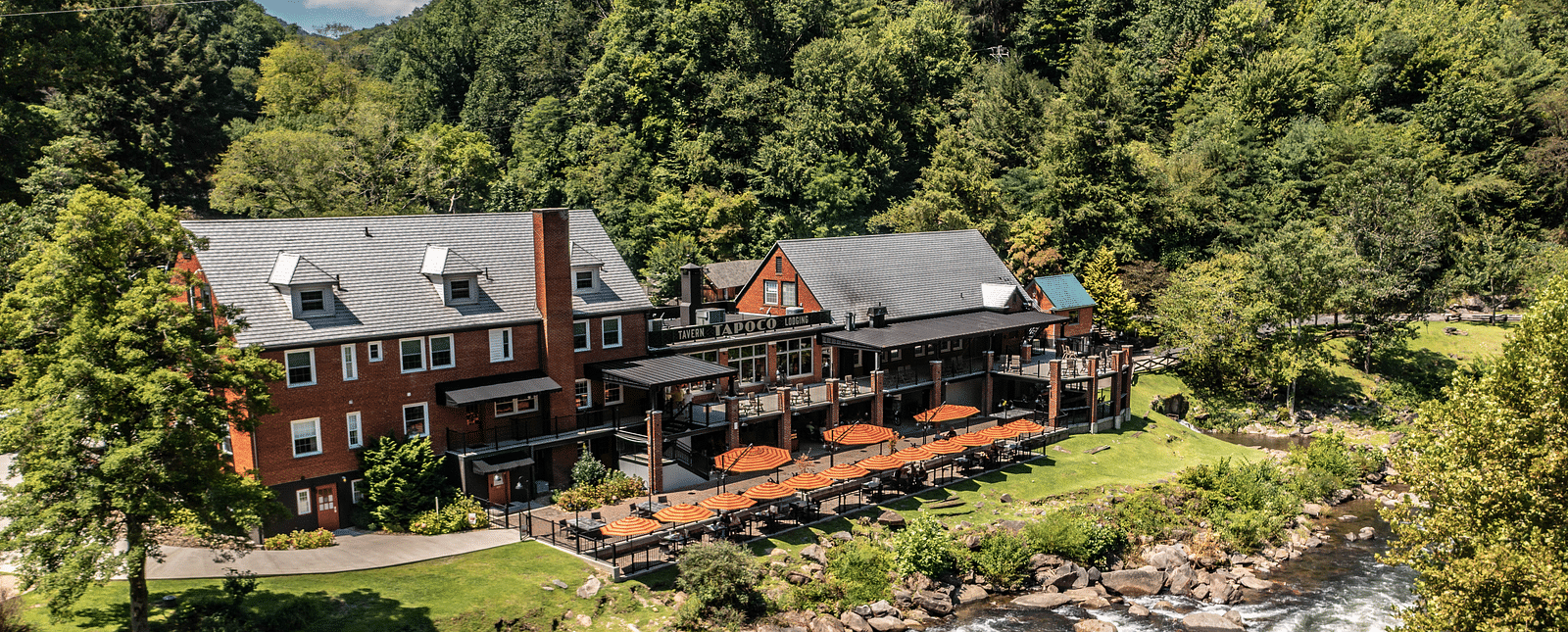 a beautiful facade image of our resort taken on a bright morning featuring a river stream flowing right in front of it - Historic Tapoco Lodge