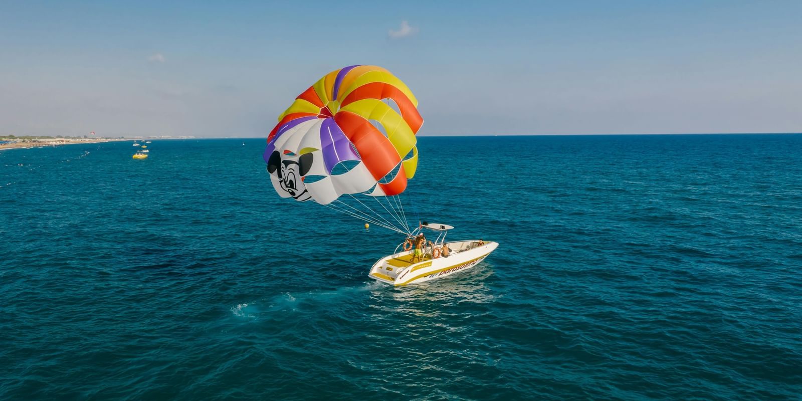 A parachute attached to a boat which is floating on a river.