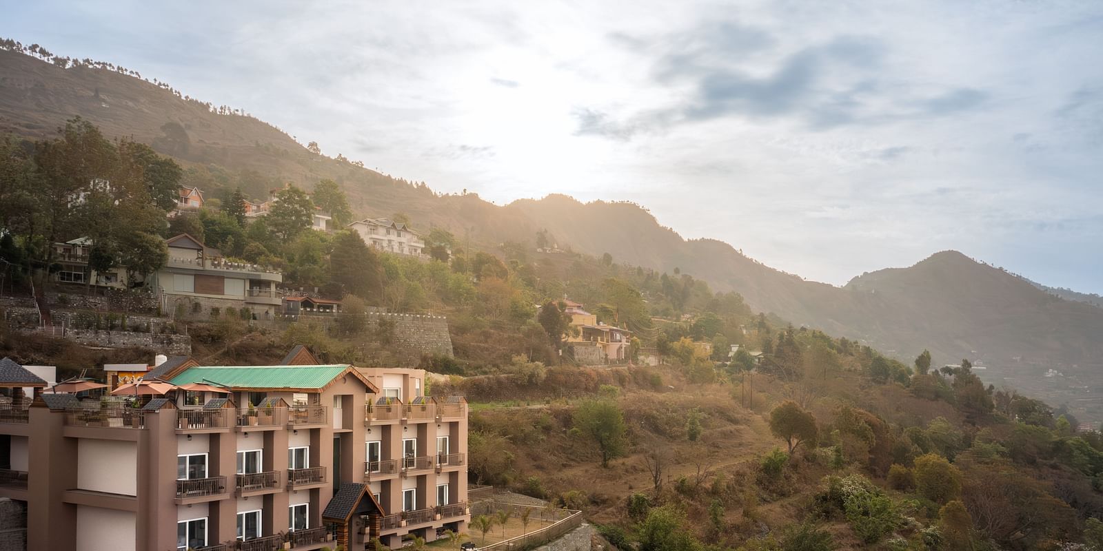 facade of the Leisure hotel surrounded by greenery with hills on the background during day v