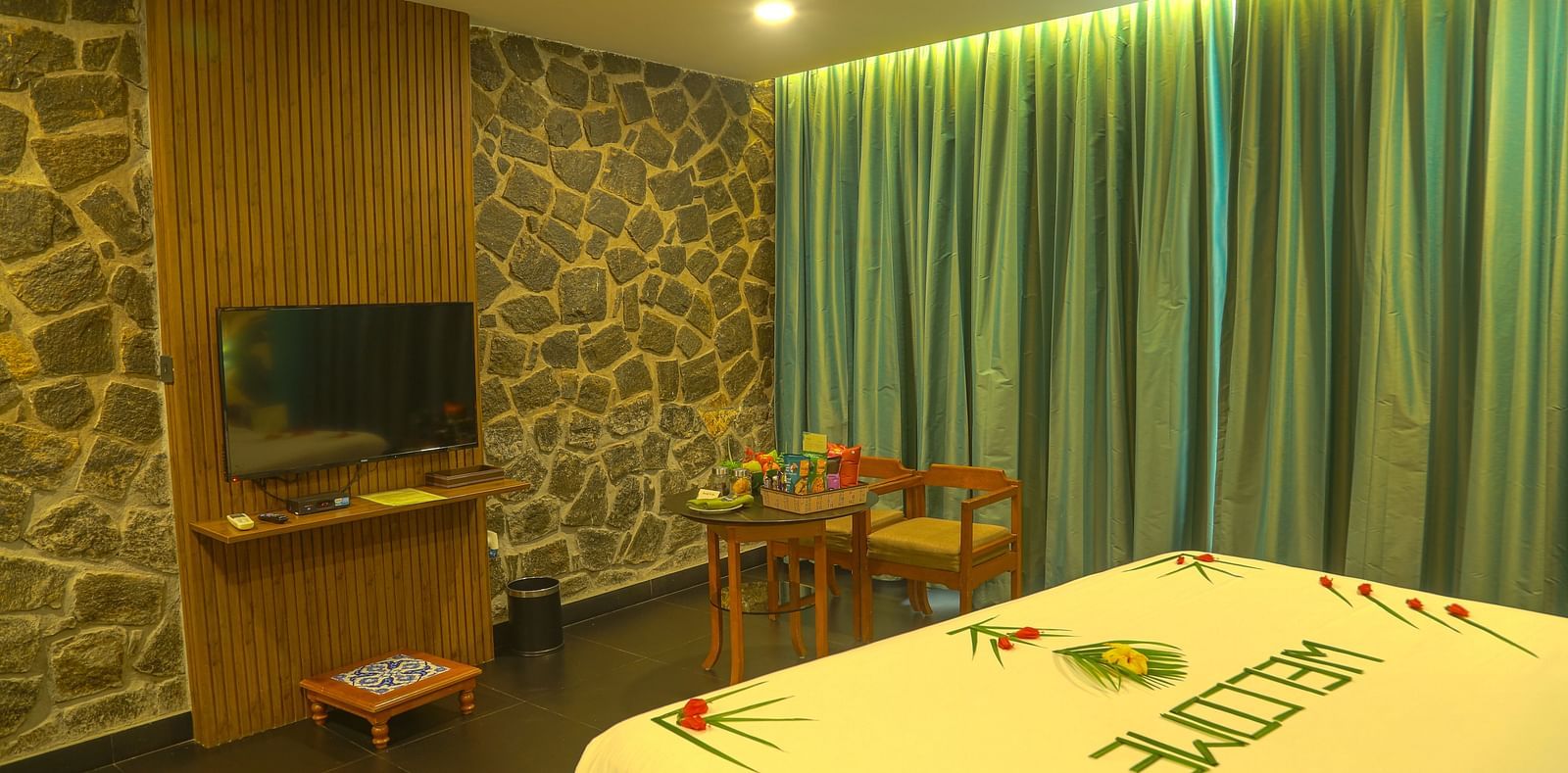 An image of a a valley view room with king size bed, bed side table, flat screen TV, wardrobe, air-conditioner, and decorative items - Great Trails Yercaud by GRT Hotels