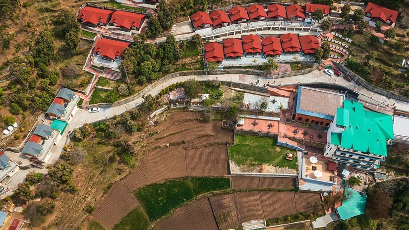   at Digantaa Resort in Mukteshwar Buildings with red roofs and other structures spread across a hilly terrain with roads