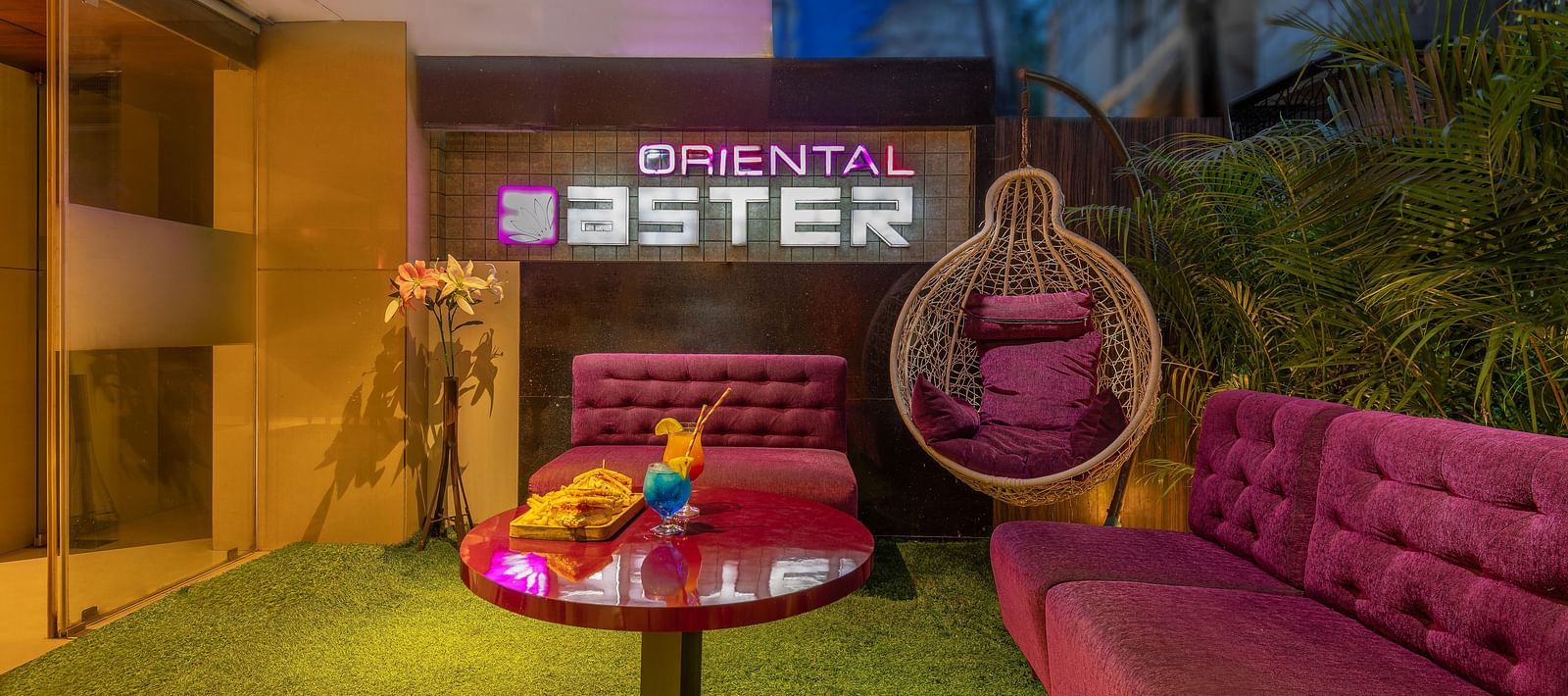 View of the lobby area at Oriental Aster, Mumbai, featuring cushioned sofas arranged around a table and a signboard displaying 'Oriental Aster'.