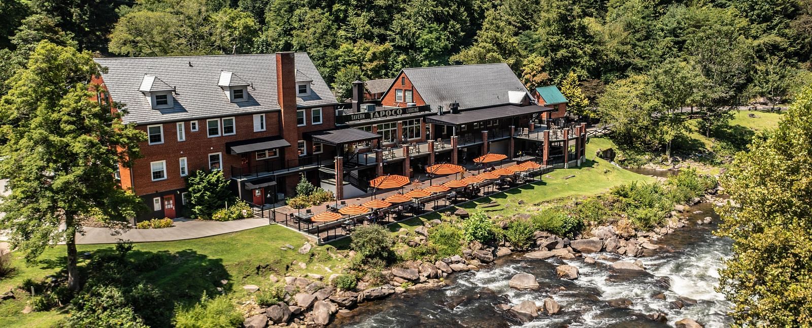 a beautiful facade image of our resort taken on a bright morning featuring a river stream flowing right in front of it - Historic Tapoco Lodge