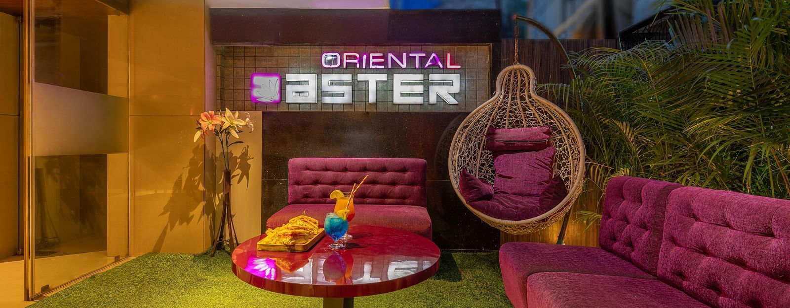 View of the lobby area at Oriental Aster, Mumbai, featuring cushioned sofas arranged around a table and a signboard displaying 'Oriental Aster'.