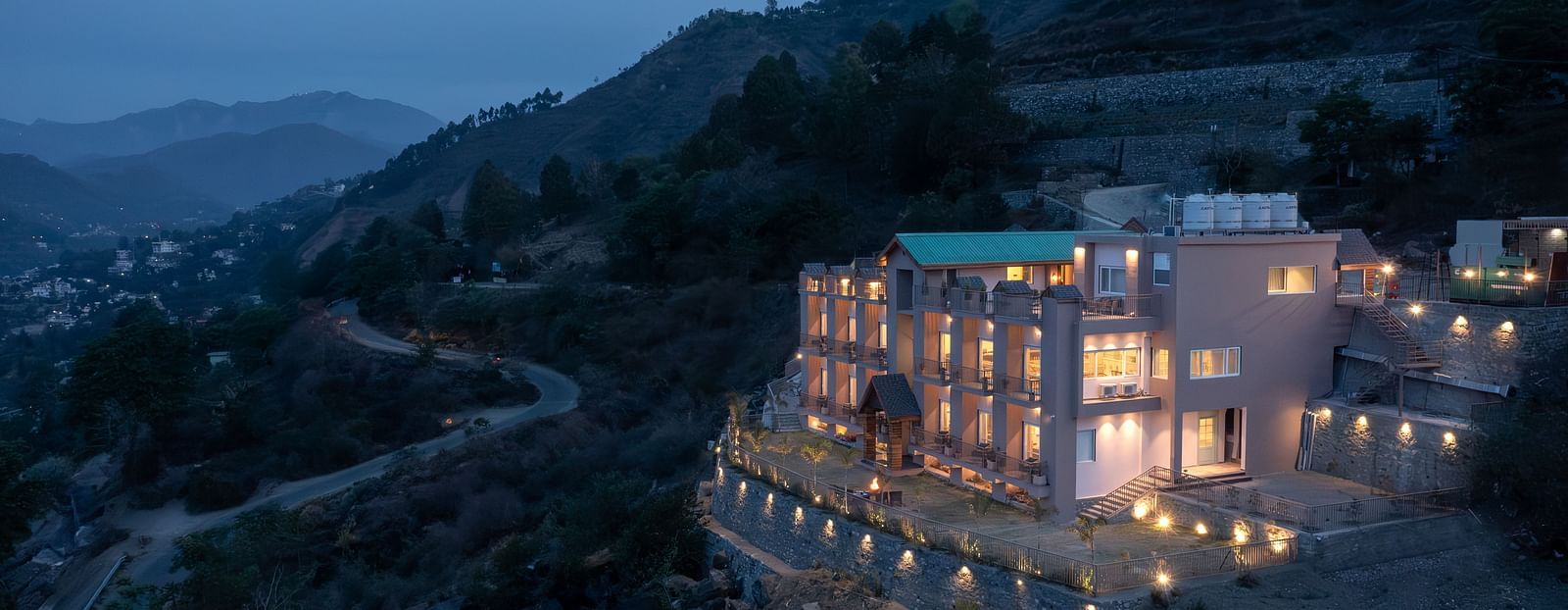picture of a Mountain view building beautifully lit in the evening, with forest in the background