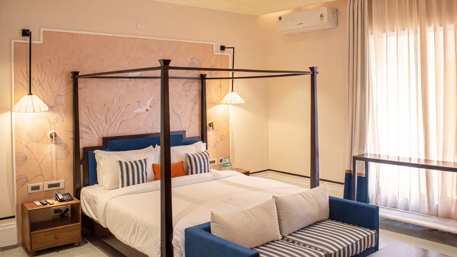 Another view of a bedroom with a four poster king size bed, attached sofa, bedside table, lamp, and curtains at The Sierra - By The Lake.