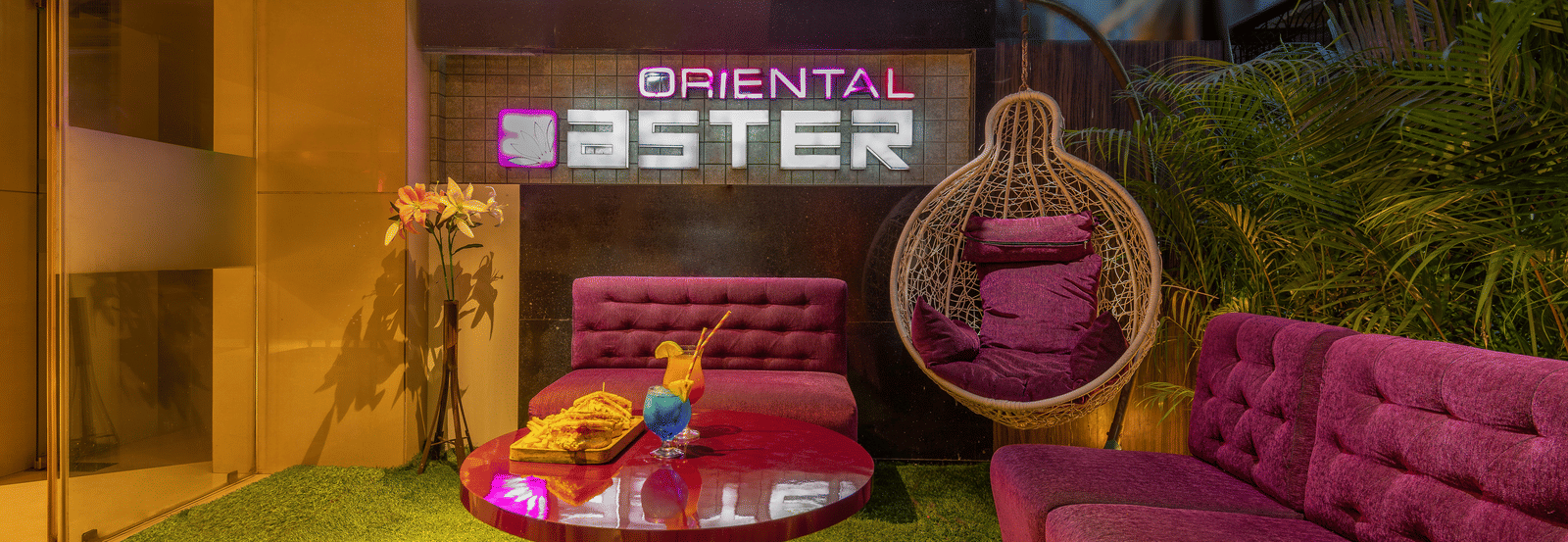 View of the lobby area at Oriental Aster, Mumbai, featuring cushioned sofas arranged around a table and a signboard displaying 'Oriental Aster'.