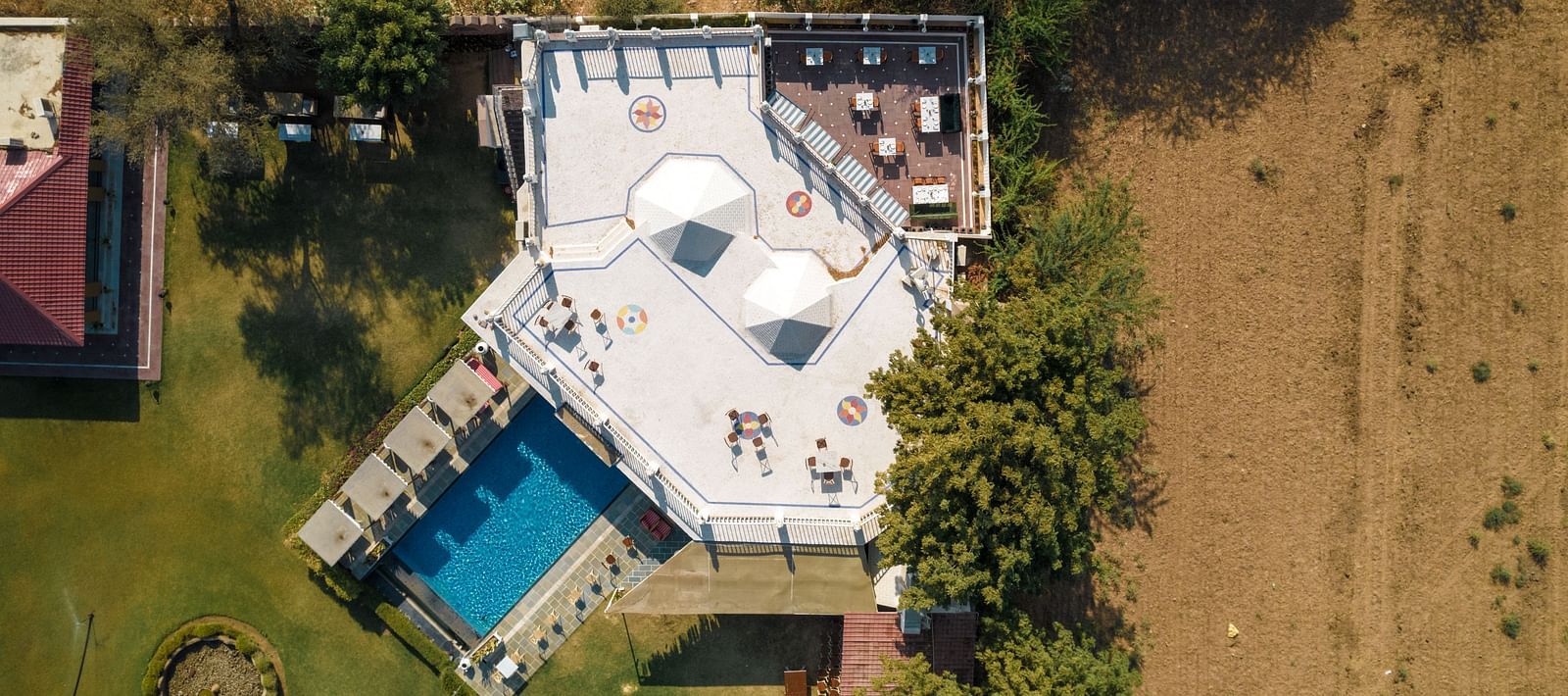 Aerial view of a dining area with a swimming pool on the side at Surpura Bagh.