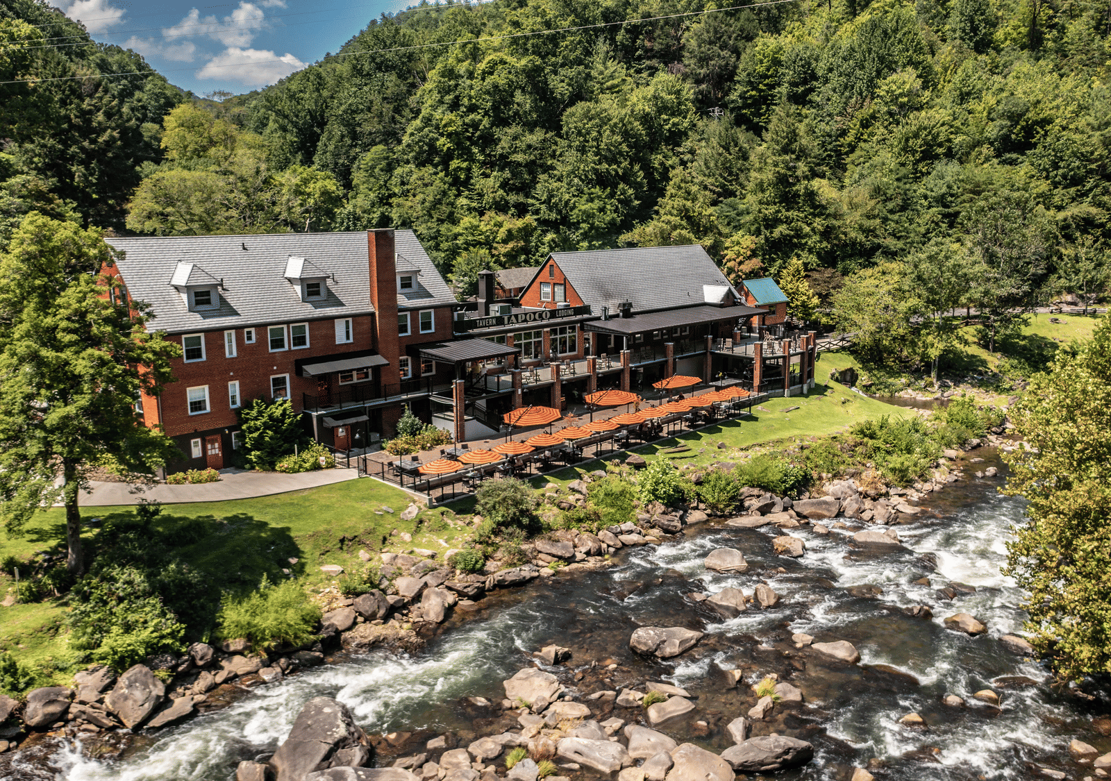 A beautiful facade of the resort taken on a bright morning featuring a river stream flowing right in front of it at the Historic Tapoco Lodge.