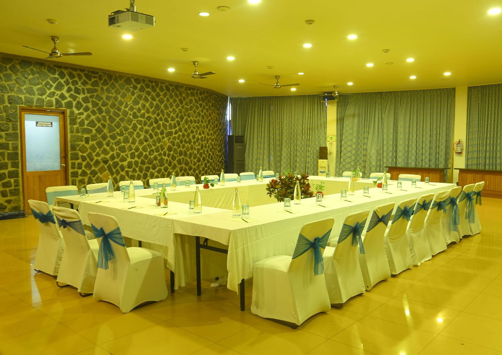 An image of the meeting hall with seating arrangement, bright lighting, and the amenities required for meetings - Great Trails Yercaud by GRT Hotels
