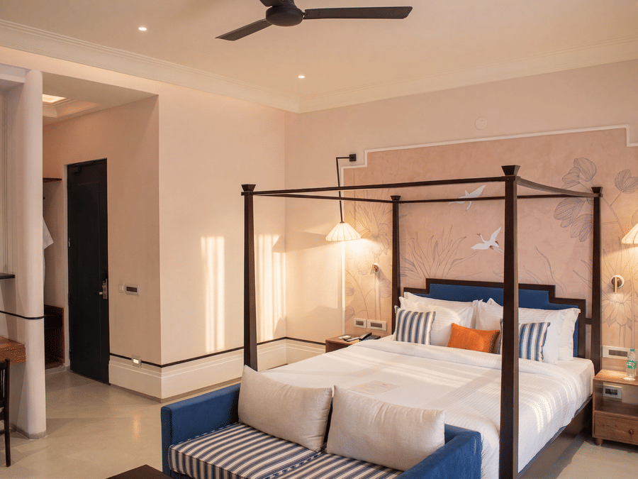 An elegant bedroom featuring a four poster king size bed, attached sofa, bedside lamps, and side desk at The Sierra - By The Lake.