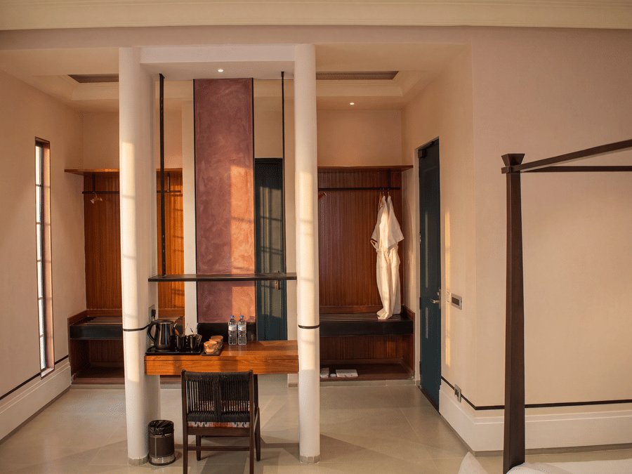 A dressing alcove with a wooden vanity desk, chair, support pillars, and hanging bathrobes at The Sierra - By The Lake.